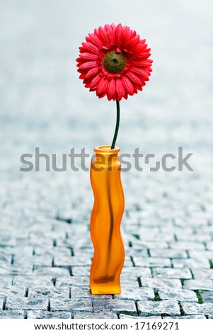 Artificial red daisy in vase on street
