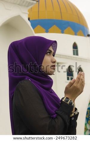 Young woman praying with mosque background