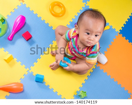 baby playing with colorful shape toy on colorful mat
