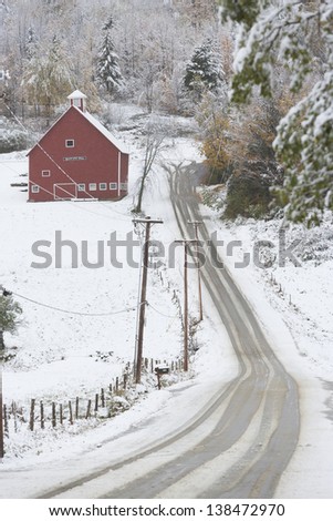 Snow covered road leading to a red barn in Stowe, Vermont, USA