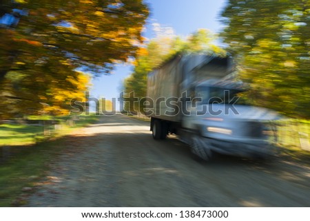 Truck moving down a rural road during fall foliage, Stowe, Vermont, USA