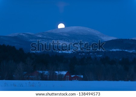 A full moon setting over a mountain behind Trapp Family Lodge, Stowe, Vermont, USA