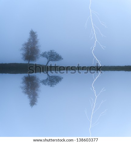 A lightning strike behind a pair of trees on a  cool foggy morning, Stowe, Vermont, USA