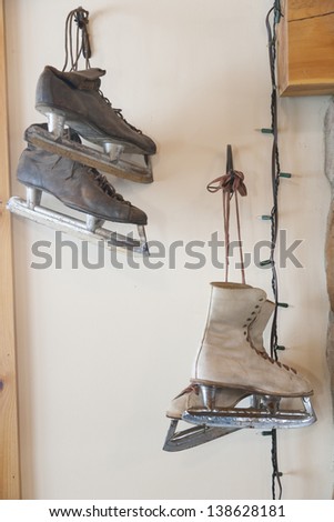 Antique pair of men\'s and women\'s ice skates hanging on the wall.