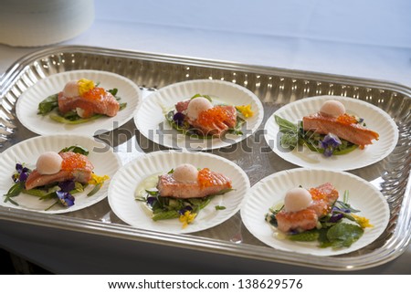 Cooked salmon dinner on a paper plate in a silver tray.