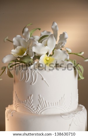 Close-up of a white wedding cake with white flowers.
