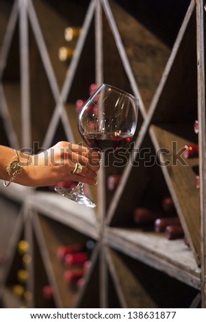 Toasting a wine glass in a wine cellar.