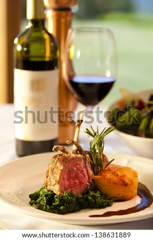 Lamb chops on a white plate with red wine.