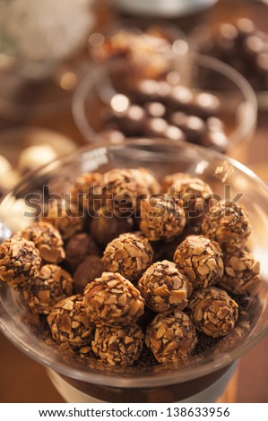 Nut and chocolate covered round candies in a glass bowl.