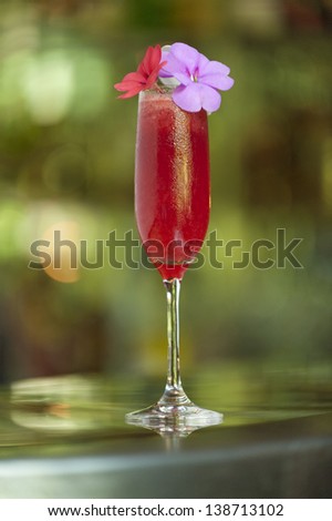 A fancy tropical cocktail drink and reflection sitting on a metallic bar.
