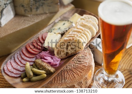 Bread, cheese in a wooden basket and a tall glass of beer.