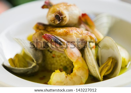 Shrimp and clam seafood appetizer on a white plate in a restaurant setting.
