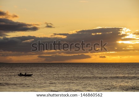 Silhouette of two men paddling a Hawaiian outrigger canoe at sunset, Maui, Hawaii, USA