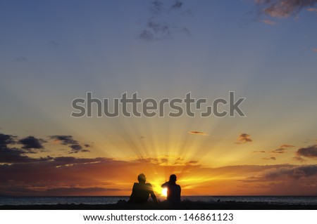Silhouette of a couple watching a colorful sunset on a beach in Maui, Hawaii, USA