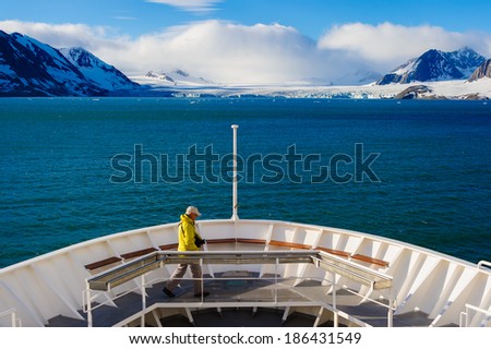 HORNSUND, SVALBARD,NORWAY - JULY 26,  2010:  Photographer on the bow of the National Geographic Explorer cruise ship in the Arctic.