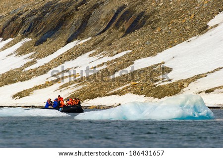 HORNSUND, SVALBARD,NORWAY - JULY 26,  2010: Tourists from the National Geographic Explorer cruise ship on inflatable rafts in the Artic Ocean exploring a fijord in the Arctic.