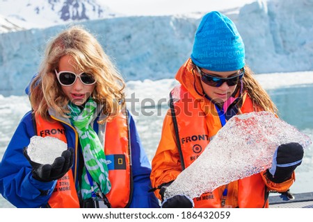 HORNSUND, SVALBARD,NORWAY - JULY 26,  2010: Young girls from the National Geographic Explorer cruise ship playing with salt water ice from the Arctic Ocean.