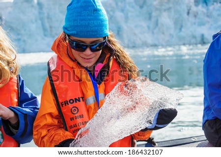 HORNSUND, SVALBARD,NORWAY - JULY 26,  2010: Young girls from the National Geographic Explorer cruise ship playing with salt water ice from the Arctic Ocean.