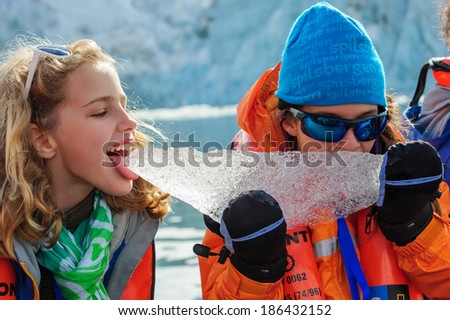 HORNSUND, SVALBARD,NORWAY - JULY 26, 2010: Young girls from the National Geographic Explorer cruise ship playing with salt water ice from the Arctic Ocean.