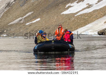 HORNSUND, SVALBARD,NORWAY - JULY 26,  2010: Tourists from the National Geographic Explorer cruise ship on inflatable rafts in the Artic Ocean exploring a fijord in the Arctic.