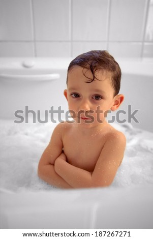 Cute young boy in bubble filled bath tub with arms crossed and attitude.