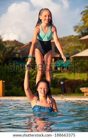 Younger girl jumping off of an older girls shoulder while swimming in a pool, Cruz Bay, St. John, USVI