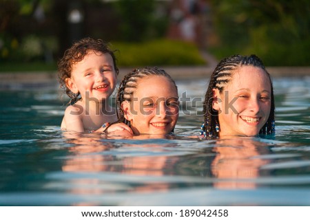 Three,children playing piggyback while swimming in a pool in Cruz Bay, St. John, USVI