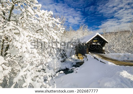 Emily\'s Covered Bridge blanketed in fresh snow on a sunny winter morning, Stowe, Vermont, USA