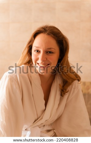 Beautiful young woman in a spa dressed in a white terry cloth robe waiting for a massage.