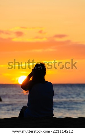 Silhouette of a woman watching a colorful sunset on a beach in Maui, Hawaii, USA