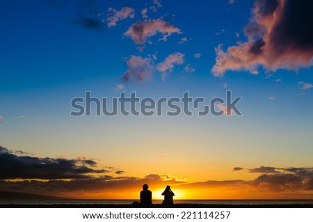Silhouette of a couple watching a colorful sunset on a beach in Maui, Hawaii, USA