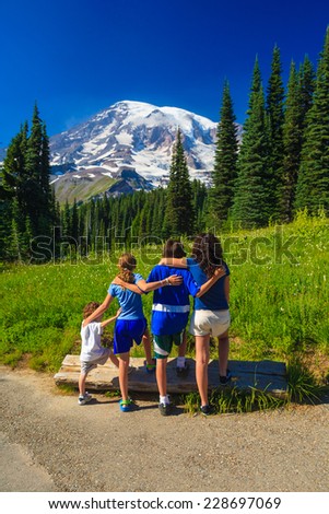 Four sibling children interlocking arms looking off at Mt. Rainier, Washington, USA