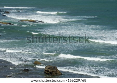 Waves, surf waves wash ashore the black sand beach of Maori Bay, Muriwai Regional Park, Auckland, North Island, New Zealand