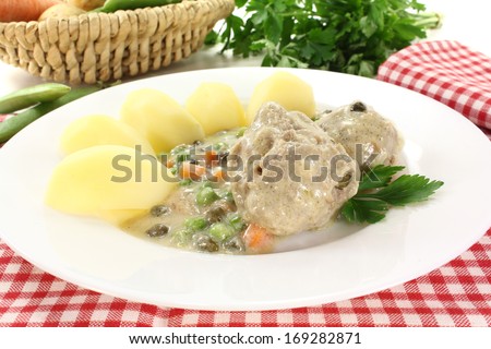 cooked meatballs in a white sauce with capers