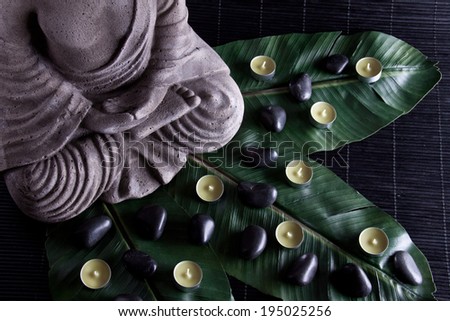 Buddha statue with massage stones on leave