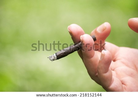 Female hand holding a lighted hand-rolled cigarett
