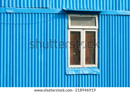 Window of blue house constructed with metal
