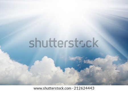The flare of the sun in the sky with white clouds