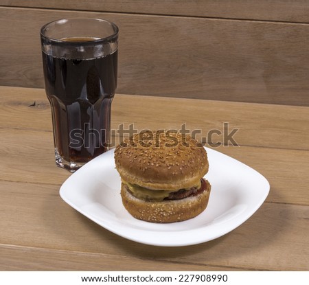 Image of burger on white plate and cola wood background