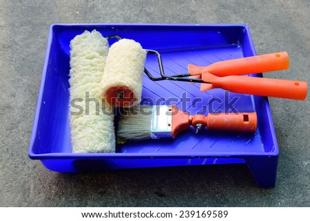 A paint tray, roller and paint brush