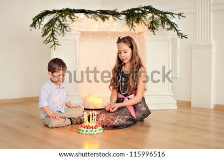 Brother and sister\'s birthday. Happy children at the fireplace