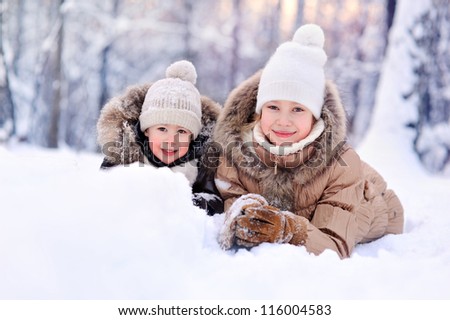 happy children lying on the snow in winter