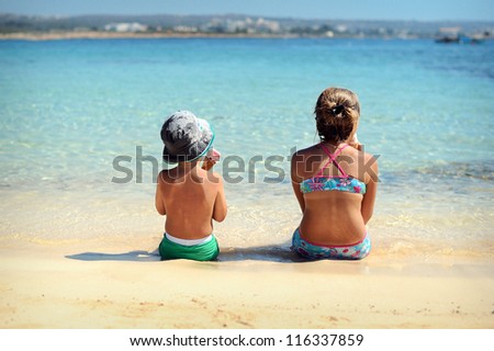 happy children sitting on the beach and eat ice cream. Sunny day by the sea.