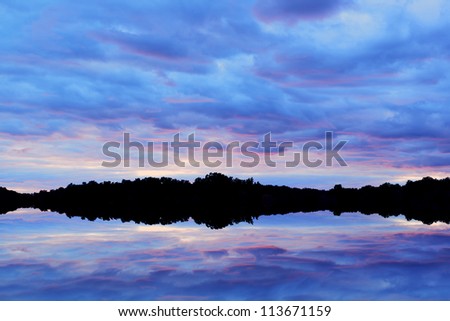 Landscape at twilight, shoreline of West Lake with reflections in calm water, Michigan, USA