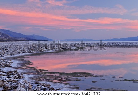 Landscape at sunset of the salt flats of Cottonball Basin with reflections in calm water, Death Valley National Park, California, USA