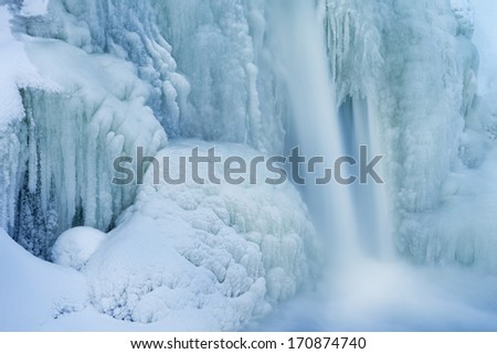 Winter landscape of the Comstock Creek cascade framed by ice and captured with motion blur, Michigan, USA