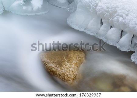 Winter creek with rock framed by icicles, Orangeville, Michigan, USA