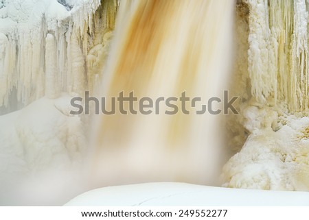 Winter, Upper Tahquamenon Falls captured with motion blur and framed by icicles and snow, Michigan\'s Upper Peninsula, USA