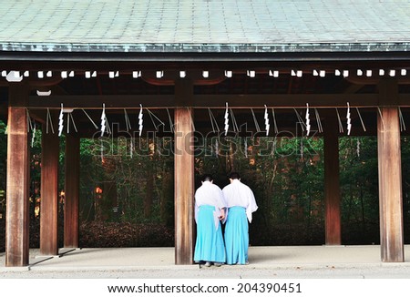 TOKYO, JAPAN - APRIL 12, 2013: Two Shinto priests in the precinct of Meiji Jingu Shrine. The shrine is dedicated to deities the Emperor Meiji and Empress Shoken, one of the biggest shrine in Japan.