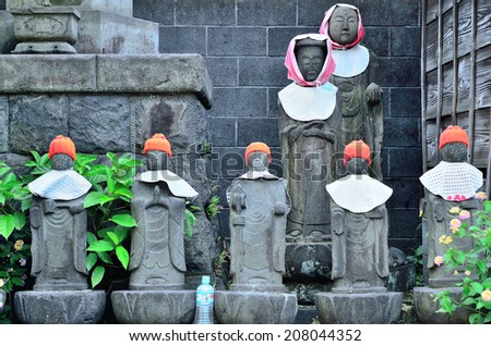 Stone statues of Jizo with red hoods offered from religious local people, in Fuji City, Shizuoka Prefecture, Japan. Jizo or bodhisattva is a guardian deity of children, travellers and the underworld.